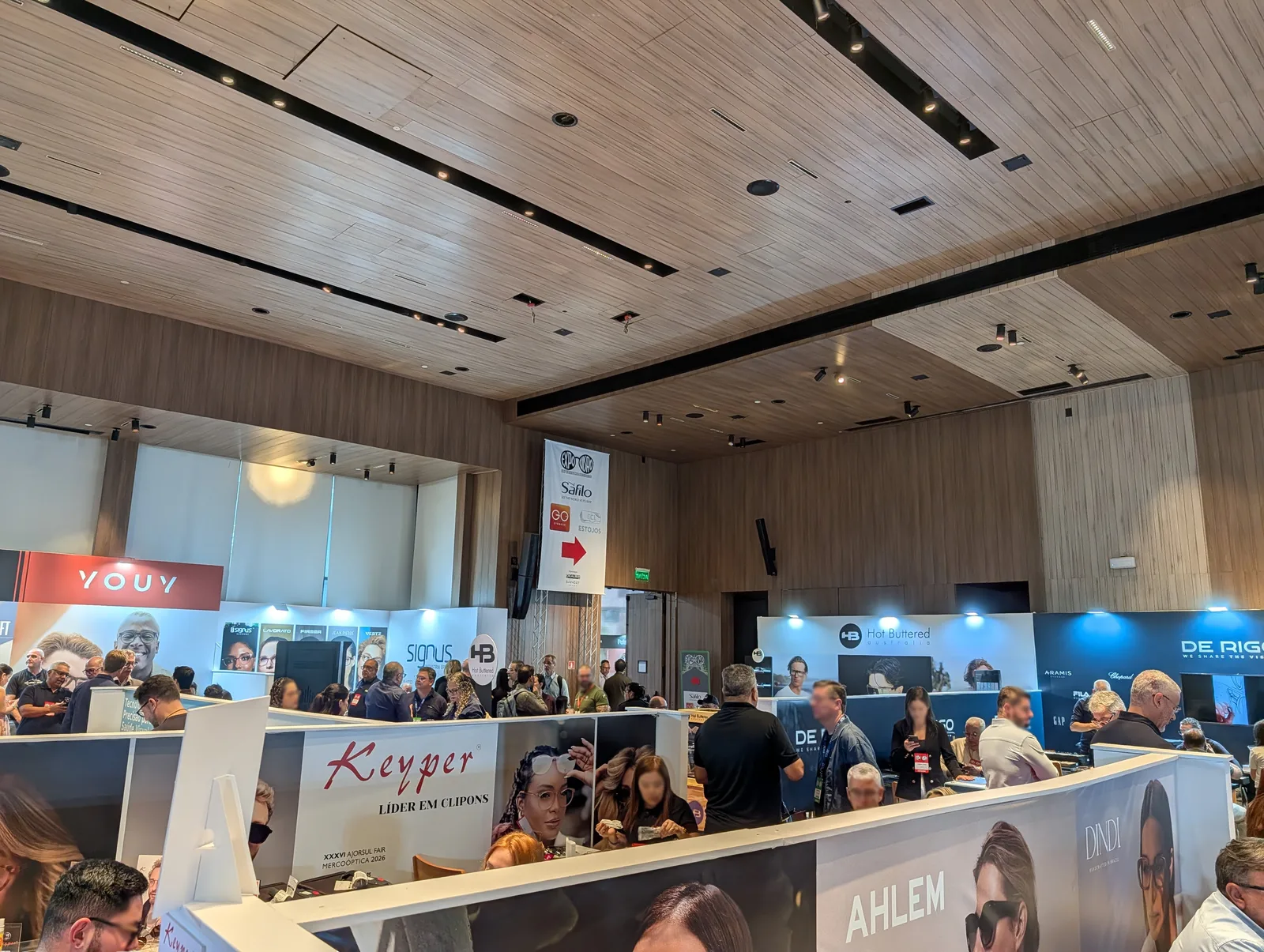 Estandes de clip-on, armações e marcas licenciadas na Expo Visão 2026, com sinalização suspensa do evento ao fundo